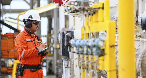 Homme en tenue de travail devant des canalisations de gaz (Istock)