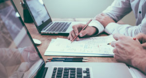 Bureau avec deux ordinateurs et des personnes qui travaillent