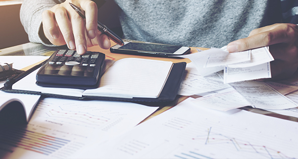 Homme sur un bureau en train de faire ses comptes (Istock)